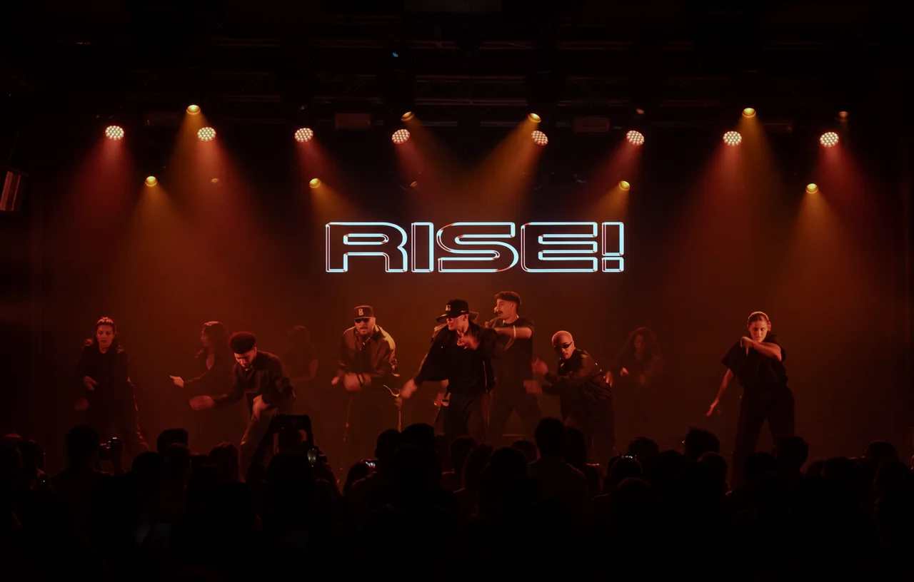 RISE! showcase stage lit in red with dancers mid-routine