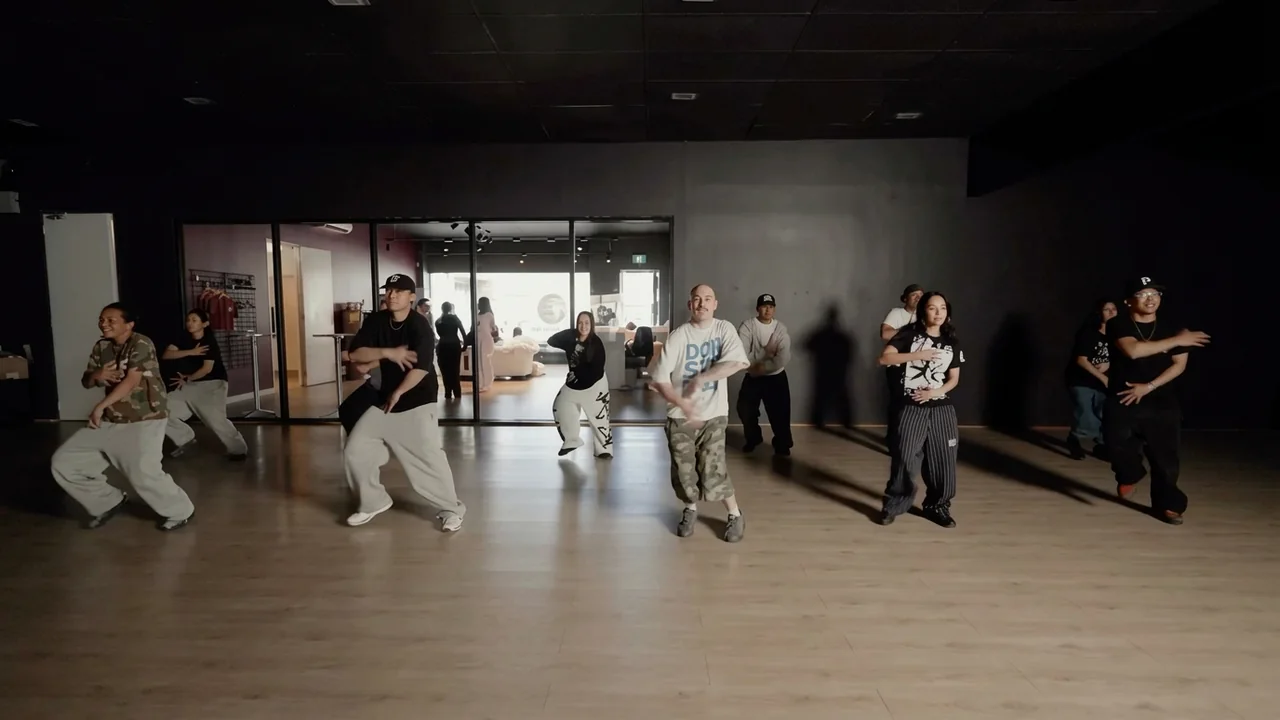 Dancers hitting a low stance in unison in the studio