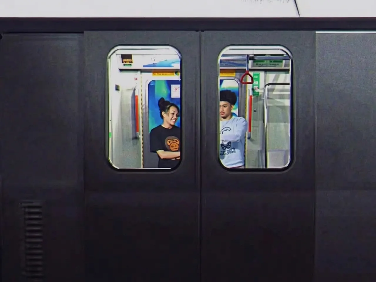 Two dancers framed in the windows of a Melbourne train carriage